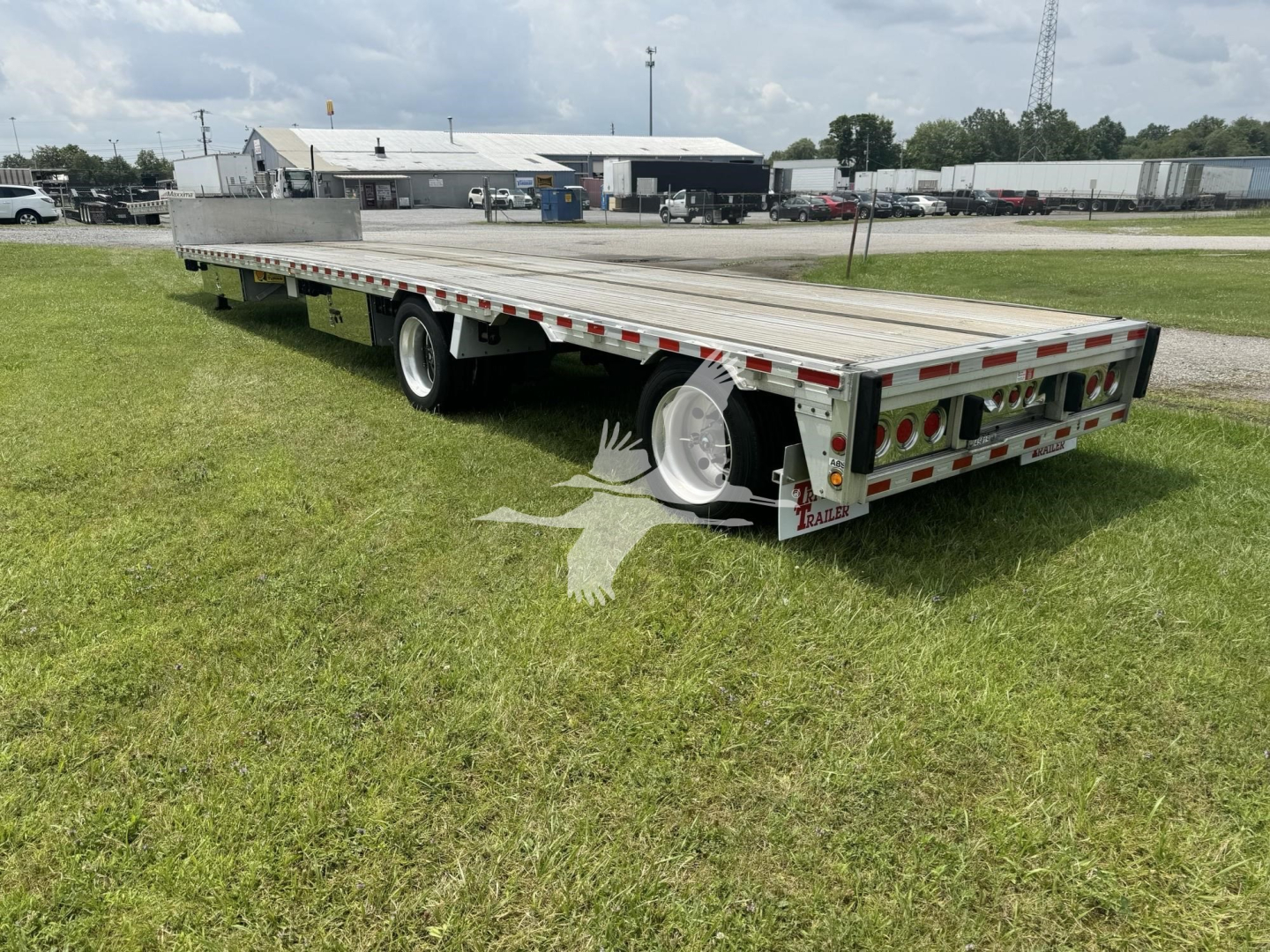 Trailer deck with drop deck design showing aluminum platform, dual rear ramps, and reflective safety tape along the sides.