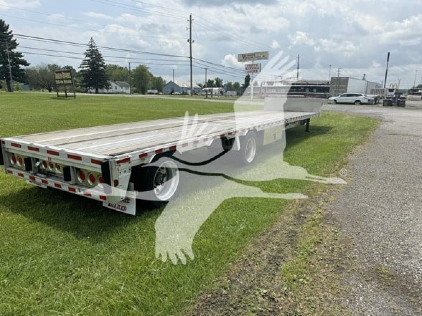Trailer: 2018 Reitnouer Dropmiser flatbed trailer from rear/side angle showing aluminum deck, dual axles, tail lights, and reflective tape.