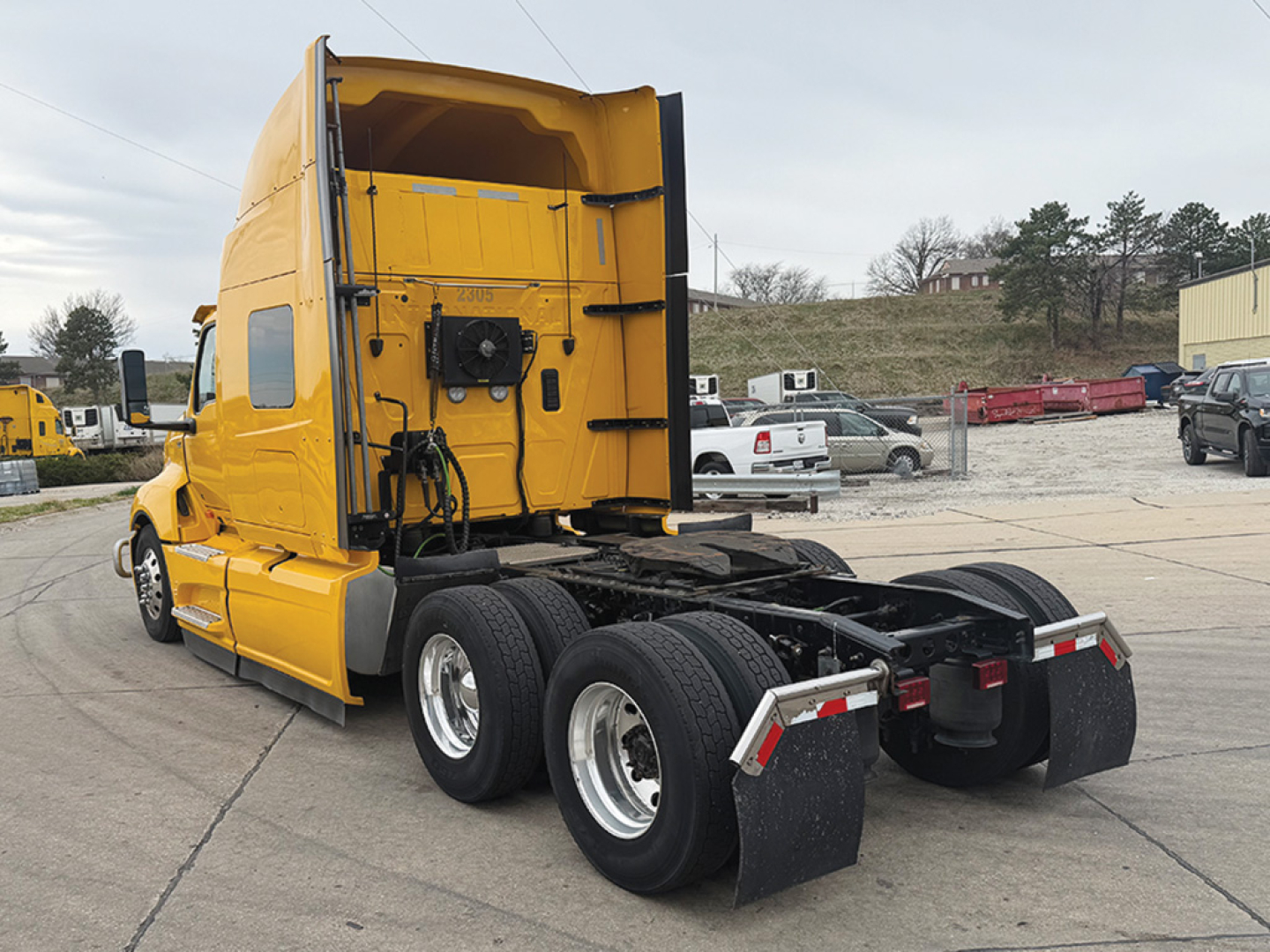 Truck cab and chassis in yellow with sleeper, rear view showing dual rear axles and fifth wheel. Visible labels include stock number plate area on cab and some engine bay text not legible.