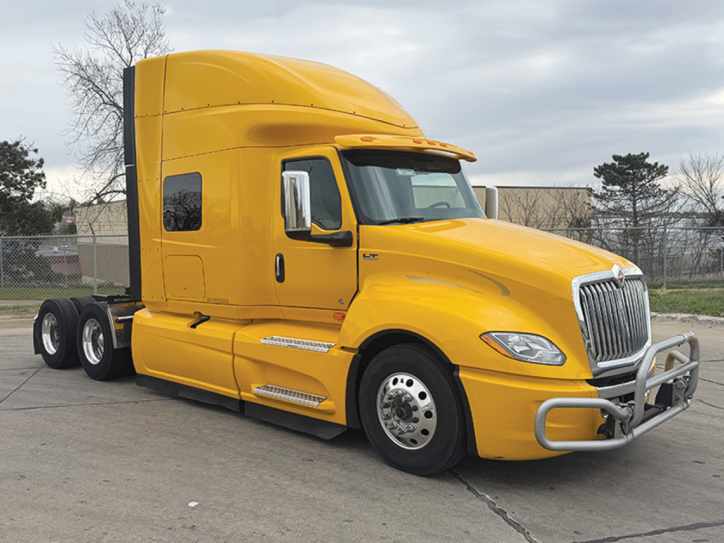 Yellow 2023 International LT625 conventional sleeper tractor from a three-quarter front-left view showing cab, chrome bumper guard, and dual rear axles.