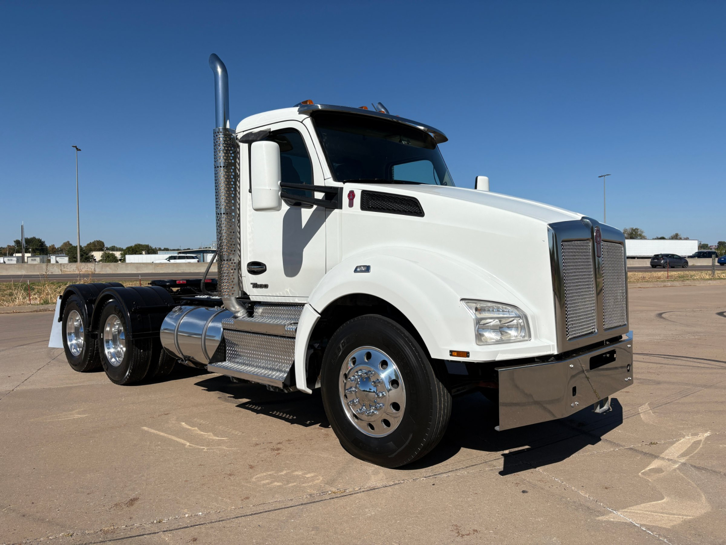 Kenworth T880 conventional daycab truck showing side view with white paint, dual rear axles, chrome exhaust, and polished wheels.