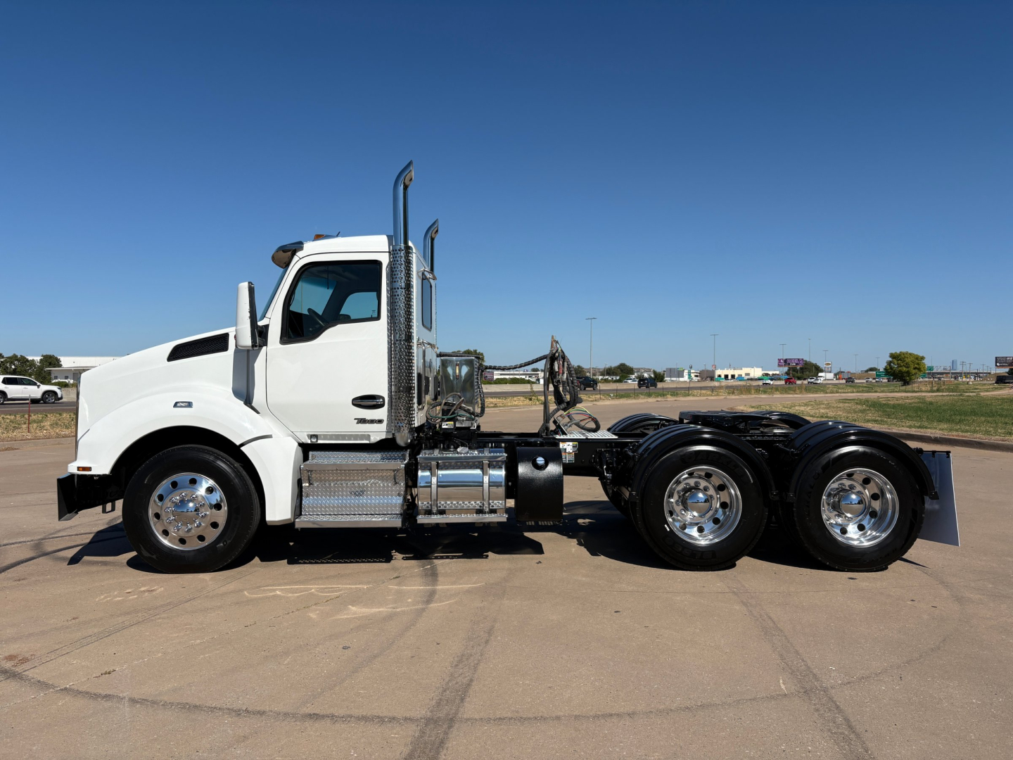 Kenworth T880 conventional daycab truck side view showing dual rear axles and chrome fuel tanks.