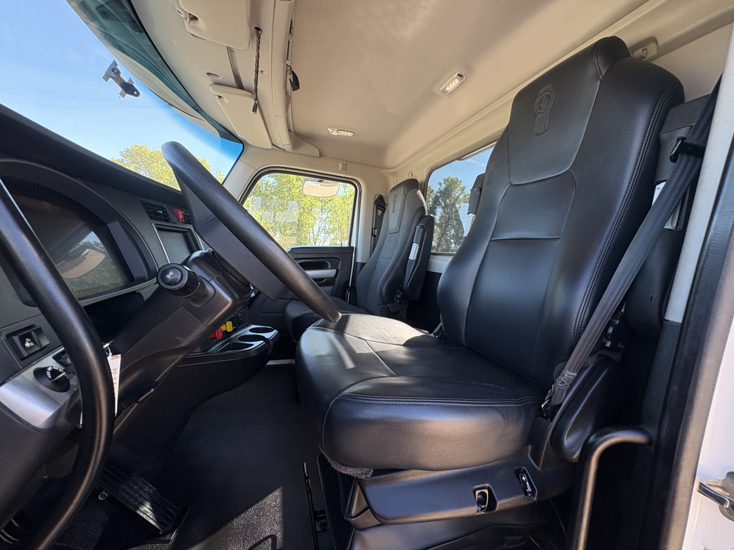 Kenworth T880 truck interior showing driver seat and passenger seat in cabin with steering wheel and dashboard visible.