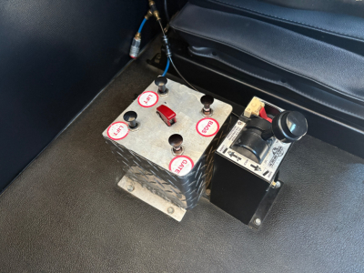 Kenworth T880 cab interior area showing a metal control block with labeled red caps and a black hydraulic/electric module attached, 2024 model year listing details in header.