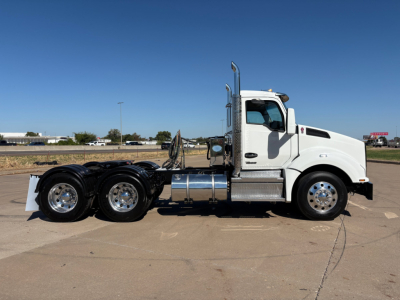 Kenworth T880 conventional daycab truck side view showing chrome fuel tanks and dual rear axles.