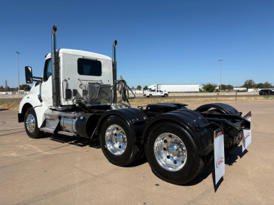Kenworth T880 conventional daycab truck chassis with dual rear axles and chrome wheels, white cab, side mirrors, and fuel tanks visible.