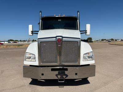 Front view of a white 2024 Kenworth T880 conventional daycab truck with large chrome grille, bumper, and side mirrors.