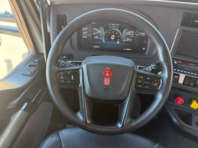 Kenworth T880 steering wheel and dashboard showing digital gauges and control stalks.