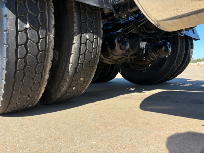 Kenworth T880 conventional daycab underside view showing tandem rear axles and suspension components.