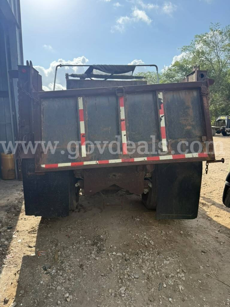 Rear view of a dump truck bed with metal panels and reflective red-and-white stripes; no legible text other than the watermark on the image.