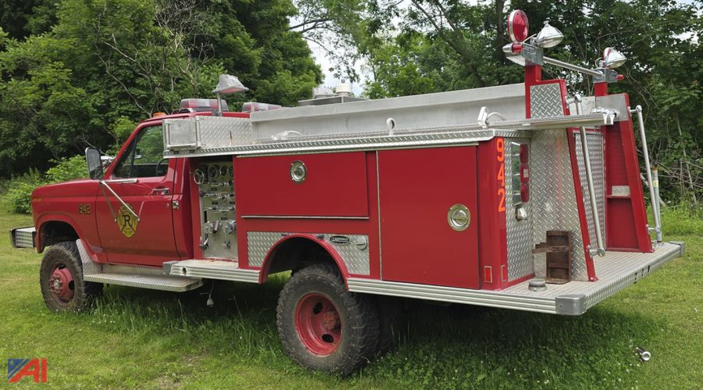 Brush fire truck 1986 Ford F-350 in-service side view showing red cab and aluminum utility body with compartments and siren lights.