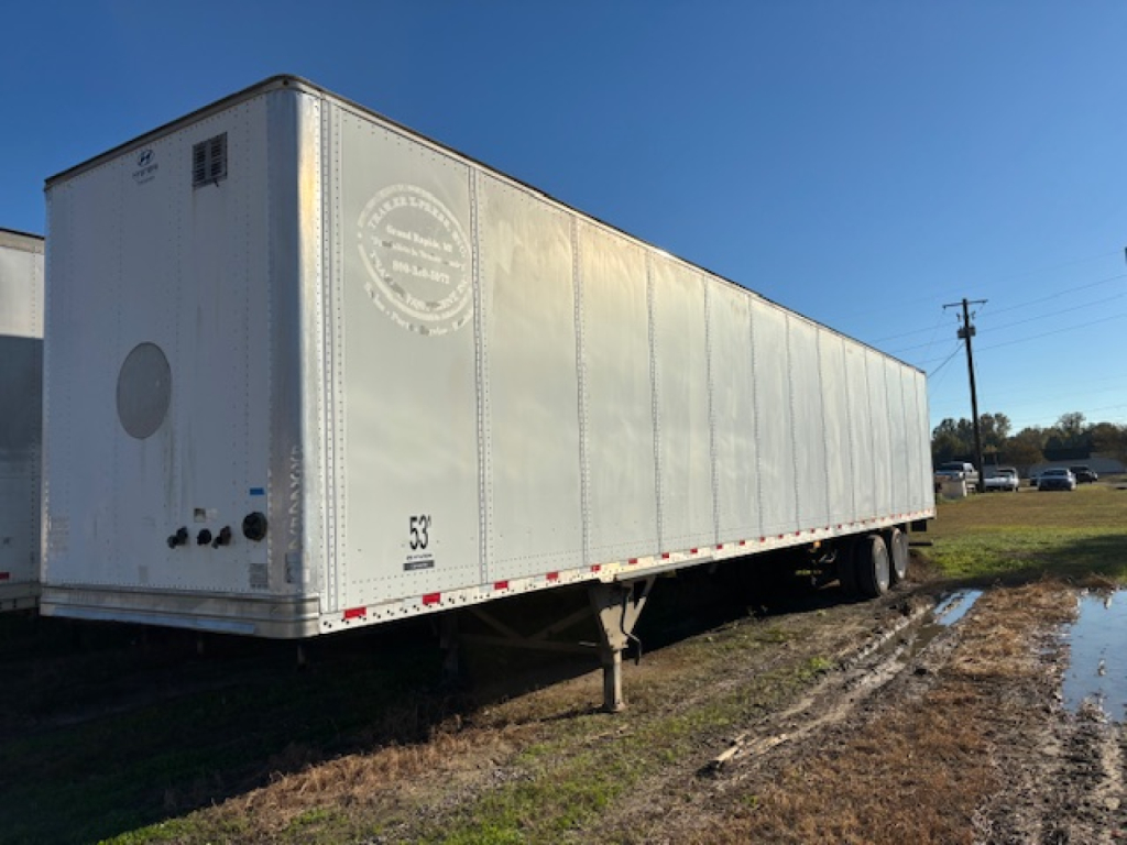 Trailer side view showing a long silver Hyundai VSRD trailer with support legs and rear doors; stock number 601, VIN 3H3V532C8GT261022 visible.