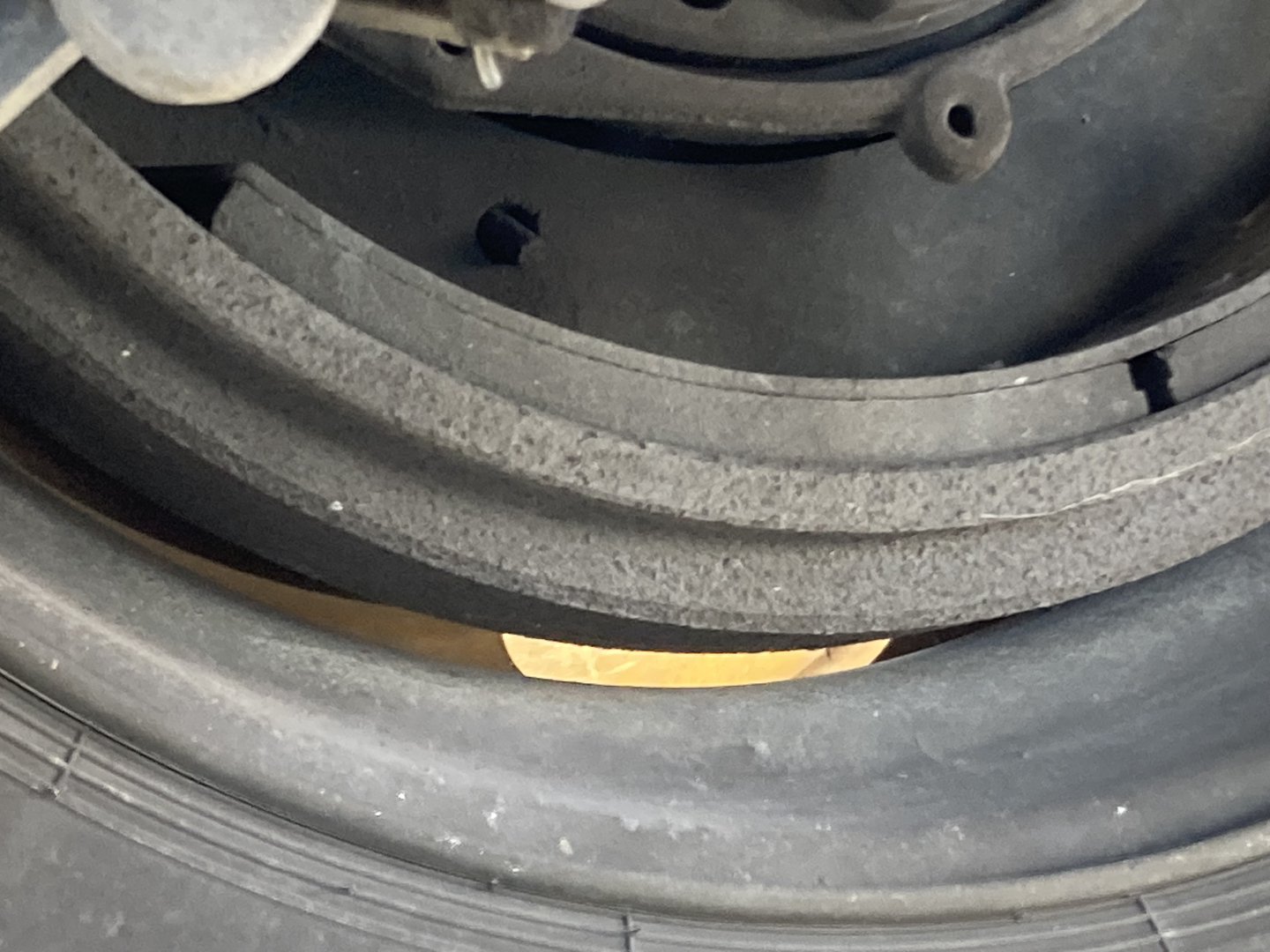 Circular components of a vehicle wheel area with layers of belts or hoses; visible is a tan label or sticker between black rings.