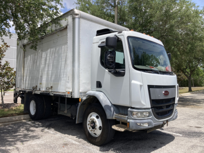 Peterbilt 220 cabover truck in white with box cargo area, front grille and headlights visible.