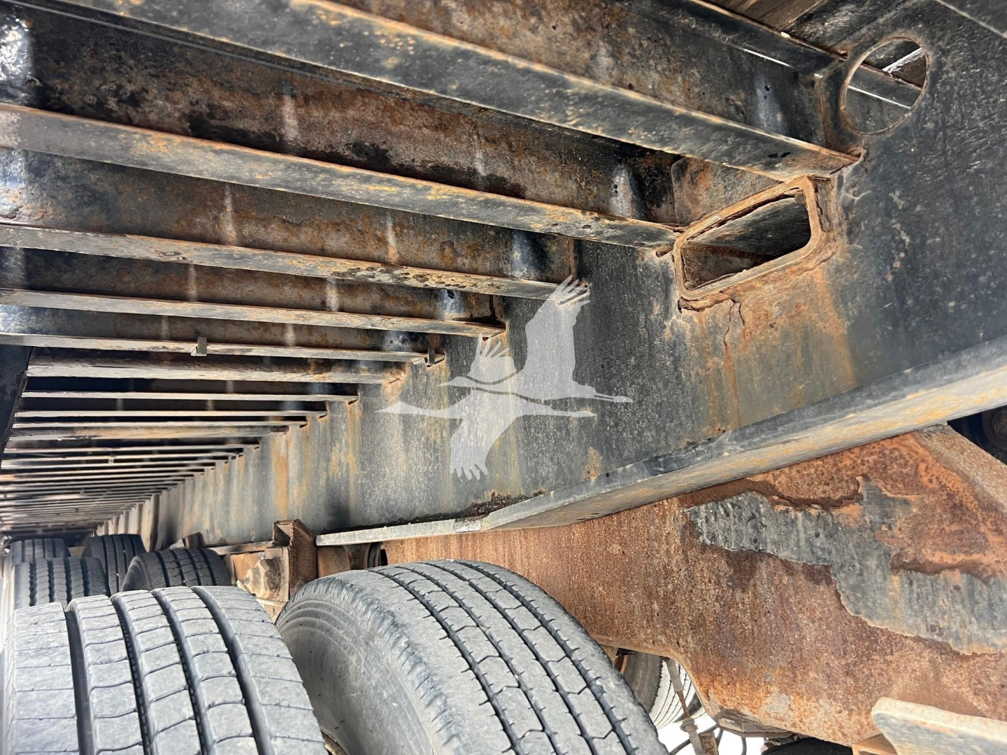 Landoll 455A-53 trailer frame with rusted undercarriage and dual wheels visible; metal beams and crossmembers; worn paint and surface residue.
