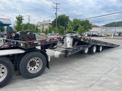 Landoll 455A-53 trailer in-use configuration showing long low-boy deck with multiple axles and tires, with some machinery and equipment on the deck
