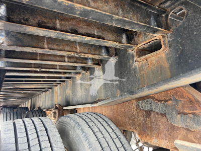 Landoll 455A-53 trailer frame with rusted undercarriage and dual wheels visible; metal beams and crossmembers; worn paint and surface residue.