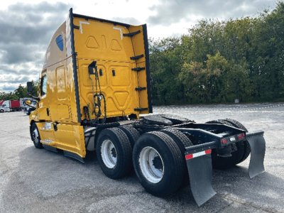 Yellow Freightliner Cascadia 126 tractor rear view showing two dual rear axles, fifth wheel area, mud flaps, and cab with door.