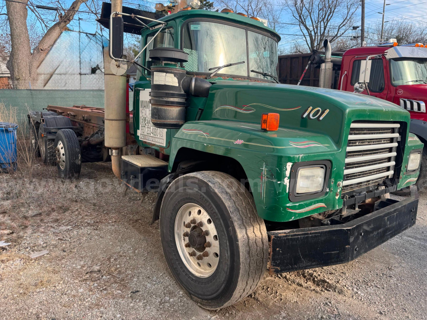 Mack RD688S roll-off truck front quarter with green cab and number 101, side exhaust stack, dual rear wheels, and flatbed area.