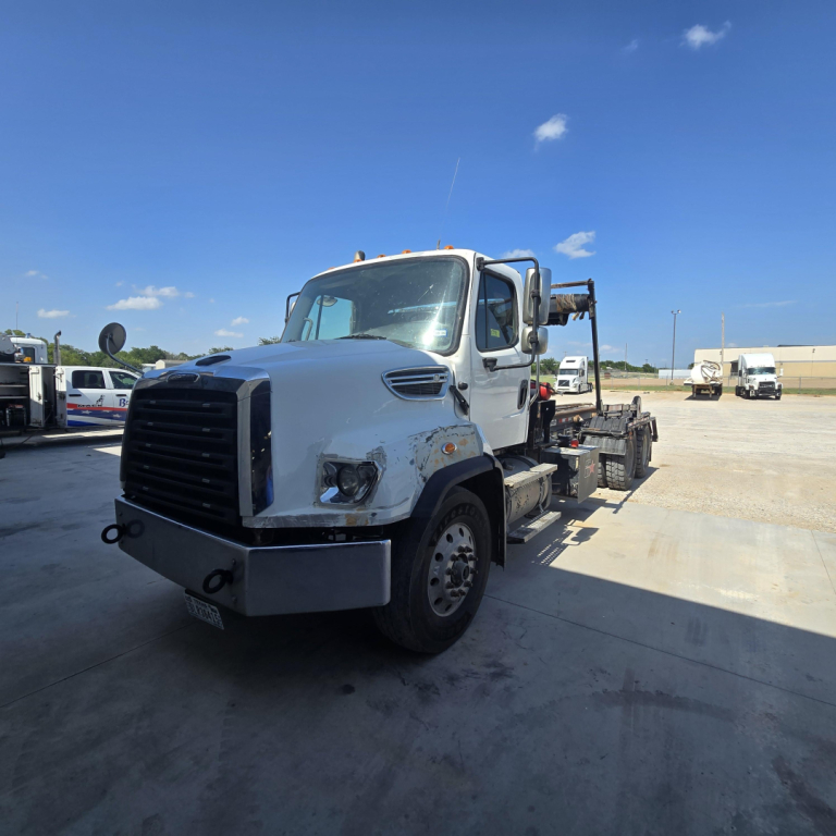 Freightliner 114SD roll-off truck in-service shown from front-left view with white cab and black bumper.