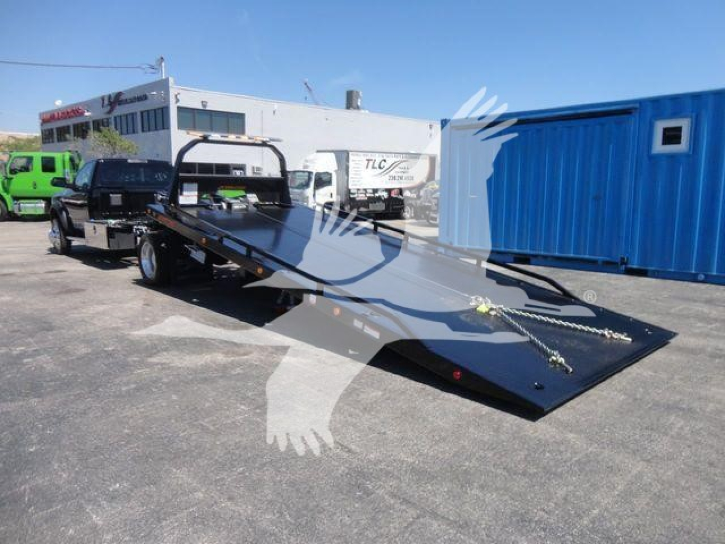 Ram 5500 rollback truck flatbed in-service showing lowered loading ramp and winch hooks.