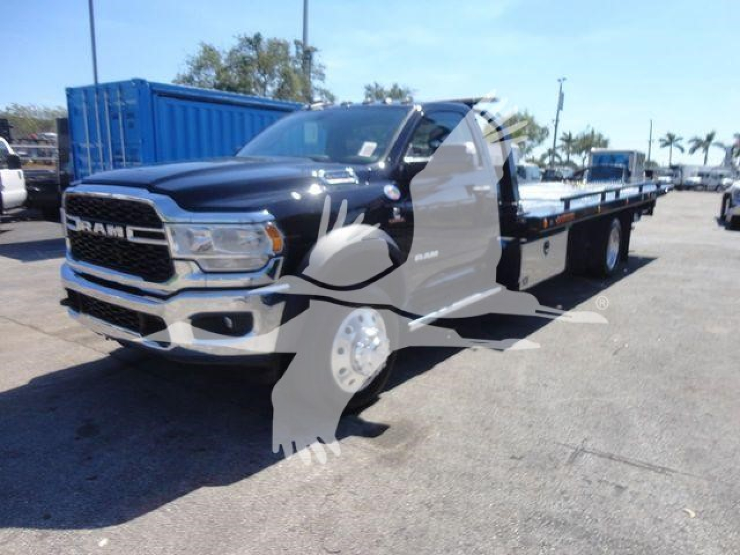 Ram 5500 rollback truck with long flatbed showing front grille and chassis in service lot.