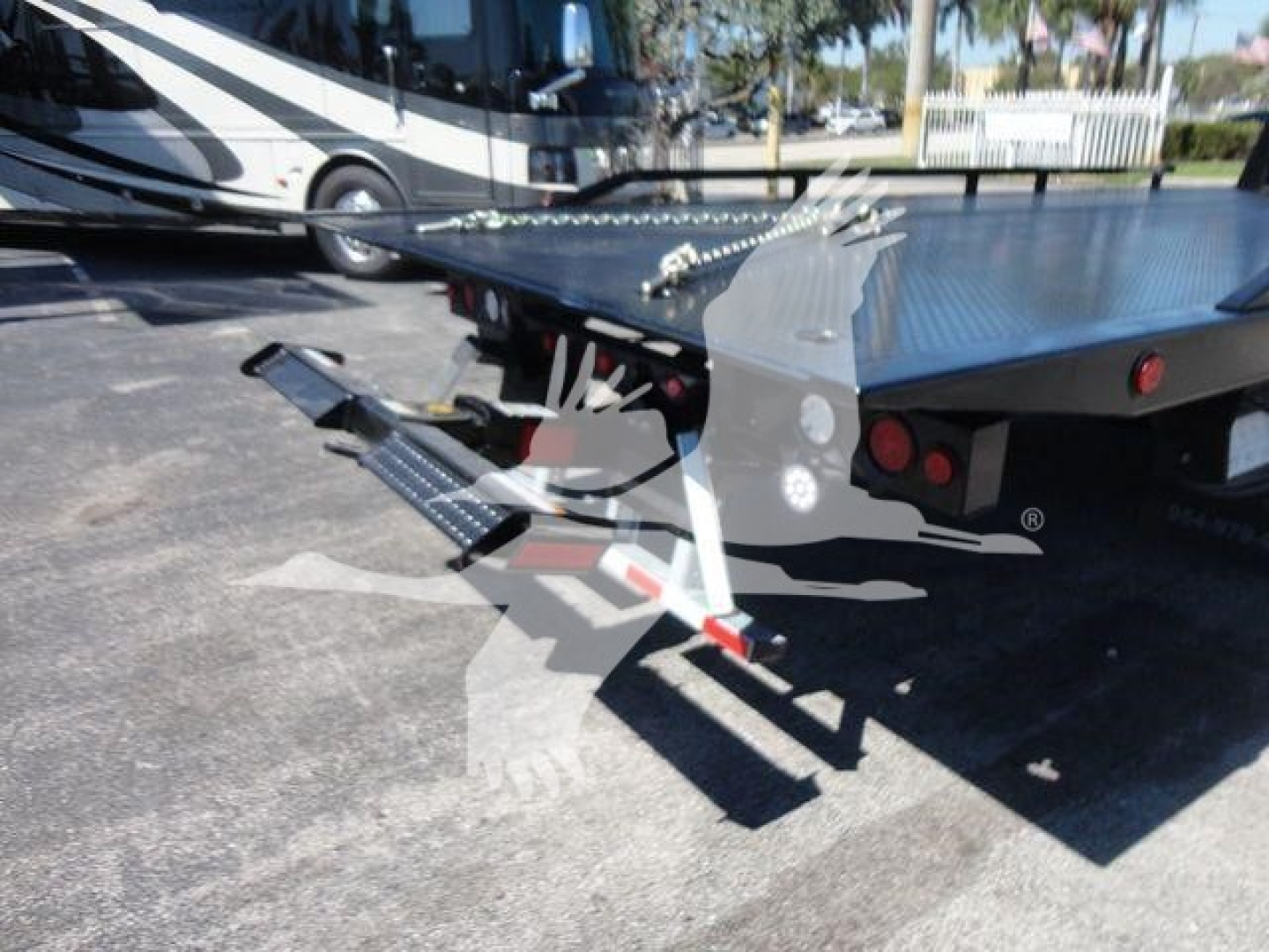Ram 5500 rollback truck bed and hydraulic system with steel ramps and dovetail, rearview showing trailer hitch and loading platform.