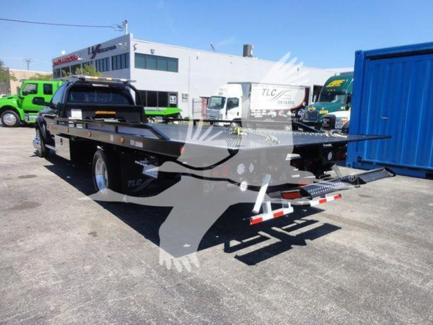 Ram 5500 SLT rollback truck with flatbed parked in lot, showing rear and side views with ramps and safety reflectors.