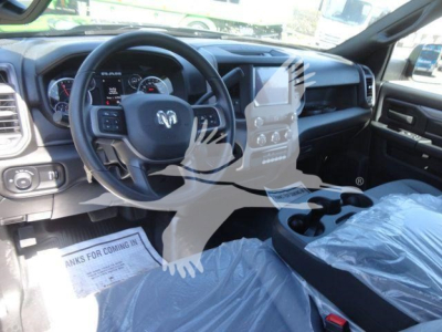 Interior front cabin of a 2024 Ram 5500 SLT showing steering wheel, dashboard, center console, and wrapped seats.