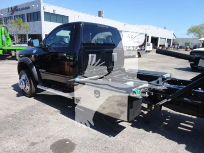 Ram 5500 truck in rollback configuration showing cab, black paint, service box, and chassis with Hook lift apparatus.
