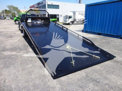 Ram 5500 rollback truck flatbed showing extended black steel platform and winch area with ramps and safety chains.