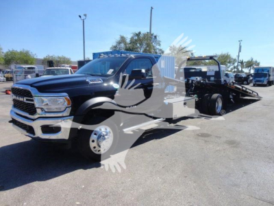 Ram 5500 rollback truck in black with flatbed, front grille and headlights visible; showroom lot in background.