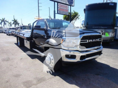 Ram 5500 rollback tow truck in dealership lot showing flatbed and front grille with RAM badge