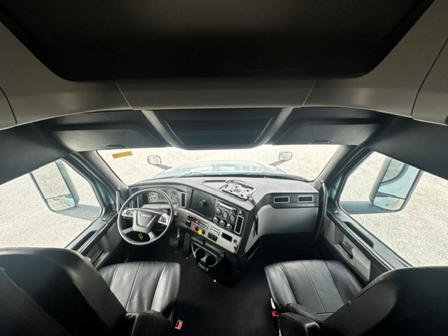 Freightliner Cascadia 126 truck cab interior showing steering wheel, dashboard, and two front seats.