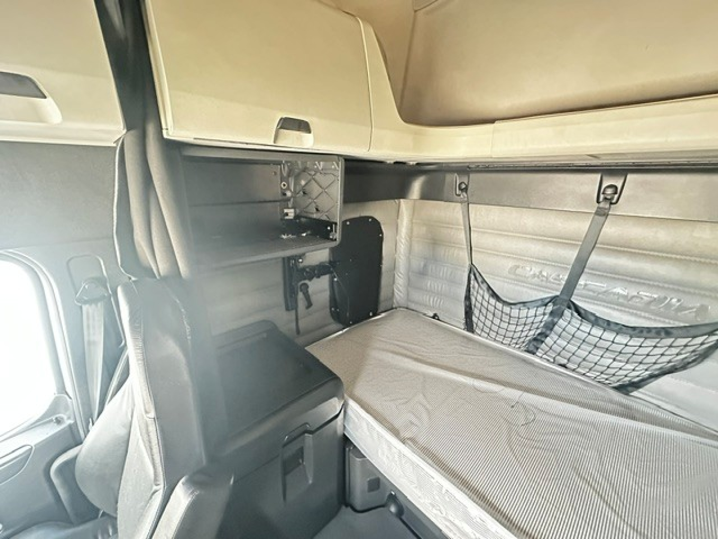 Cab interior of a 2023 Freightliner Cascadia 126 sleeper showing bunk area and storage compartments.