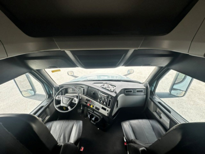 Freightliner Cascadia 126 truck cab interior showing steering wheel, dashboard, and two front seats.