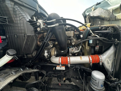 Truck engine bay with hoses, hoses, and intercooler piping; visible components include air intake, coolant hoses, and turbocharger area.