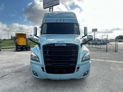 Front view of a light blue 2023 Freightliner Cascadia 126 sleeper tractor in a dealership lot, showing the grille, headlights, mirrors, and windshield.
