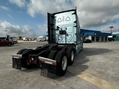 Freightliner Cascadia 126 semi-truck tractor rear view showing dual rear axles, mud flaps, and back of cab with sleeper, in a truck yard