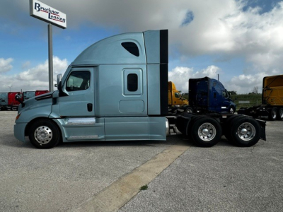 Truck cab side view showing 2023 Freightliner Cascadia 126 with sleeper, blue cab, diesel engine, tandem rear axles, fuel tanks, and storage compartments.