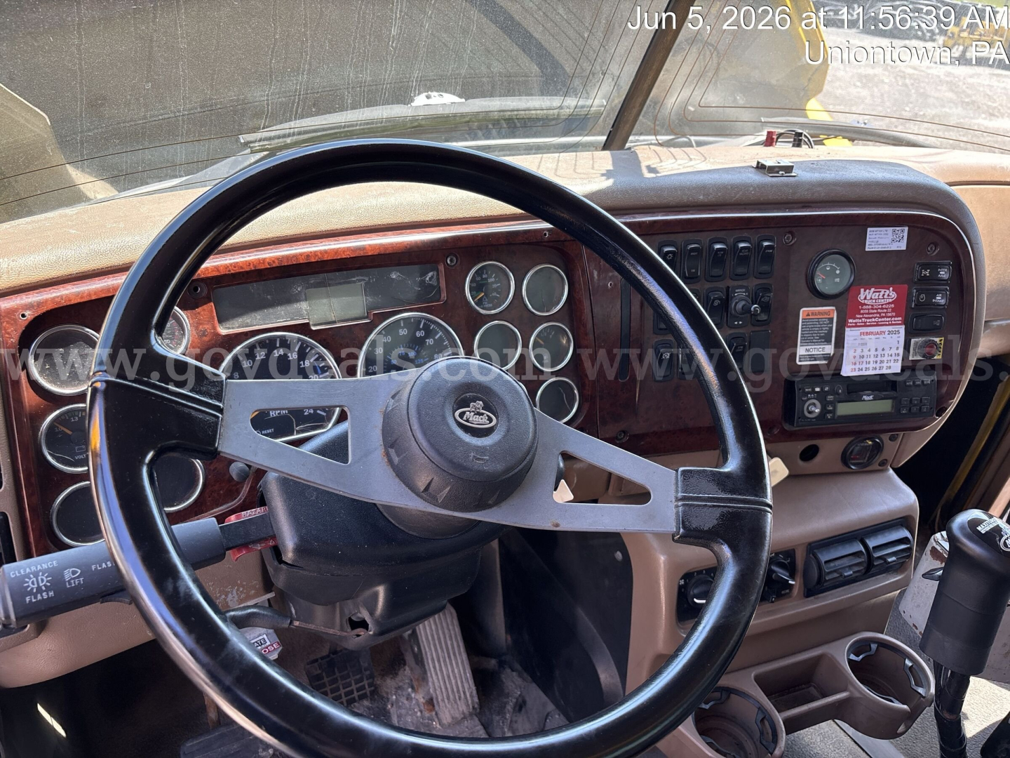 Dashboard of a Mack CV713 dump truck showing steering wheel, gauges, and control panel. Visible text includes various gauges and small labels on the dash.