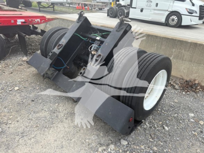 Talbert flip axle trailer component with dual wheels and hydraulic/mechanical mounting, viewed from side on gravel.