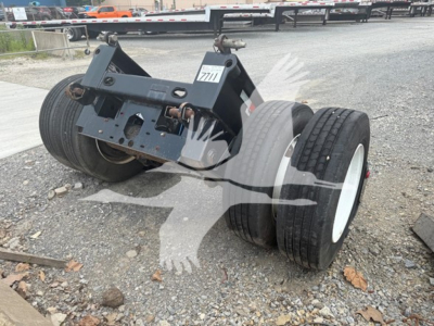 Talbert flip axle trailer component with dual tires and mounting bracket seen on gravel surface.
