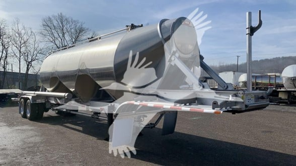 Heil cementer trailer in a yard showing a cylindrical stainless steel tank mounted on a dual-axle trailer.
