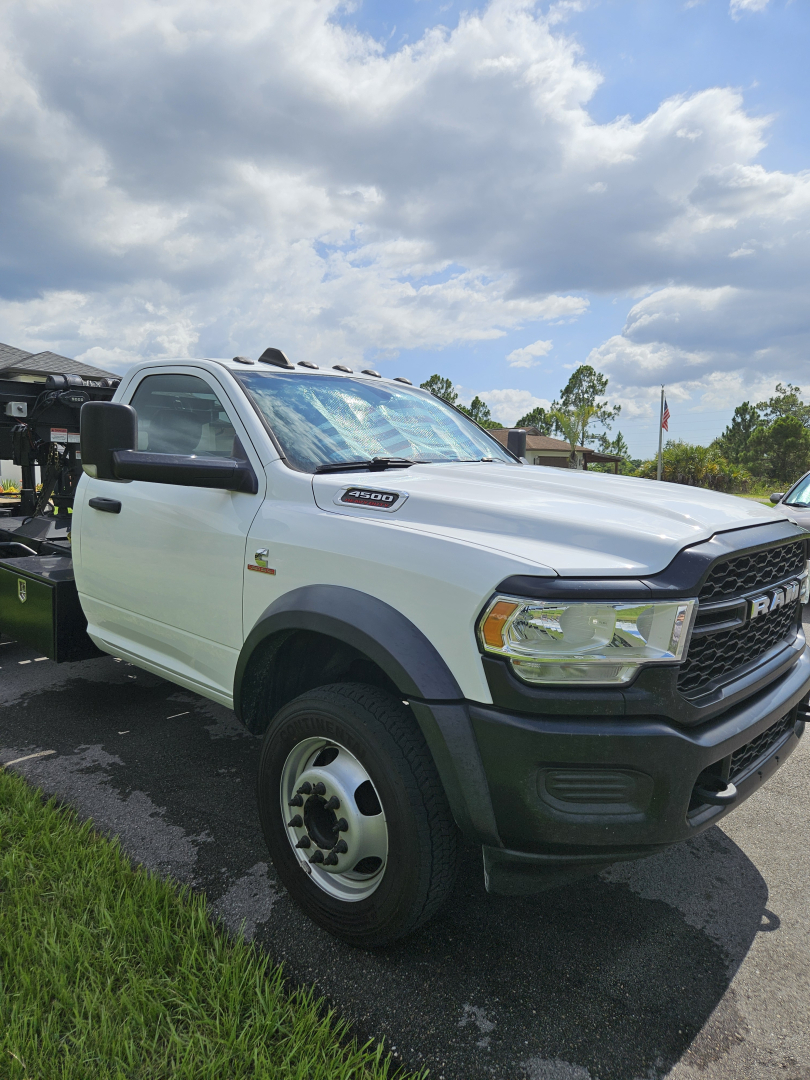 2021 Dodge Ram truck in white with black grille and fender, front-left view, badge on side, large side mirrors.