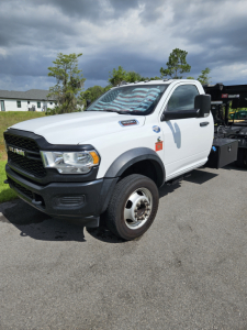 Dodge Ram truck in white with black front bumper and dual rear wheels visible, side view of cab, VIN plate not legible.
