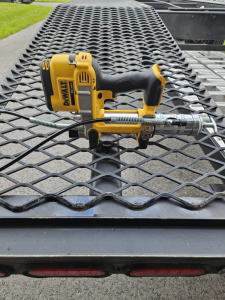 DeWalt cordless impact driver mounted on a metal mesh truck bed with a hydraulic hose or connector attached.