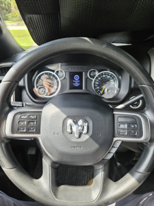 Steering wheel of a 2021 Dodge Ram shown from driver seat with instrument cluster and center display visible.