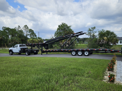 Flatbed tow truck with long multi-axle trailer and hydraulic arm, visible in side profile