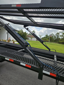 Truck equipment: a car hauler or tow bed with hydraulic arms and metal grated platform